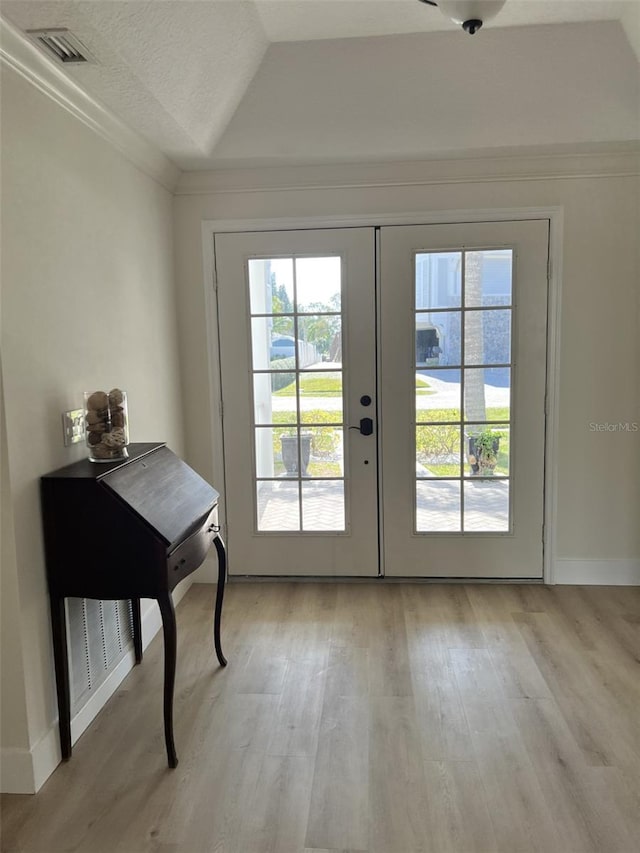 doorway featuring vaulted ceiling, a textured ceiling, light hardwood / wood-style floors, and french doors