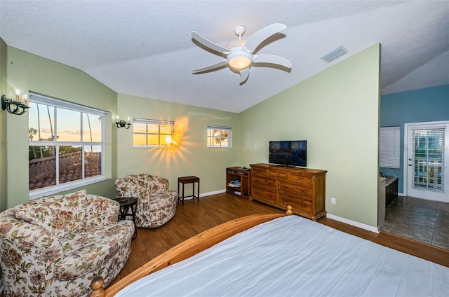 bedroom with dark wood-type flooring, lofted ceiling, multiple windows, and a textured ceiling