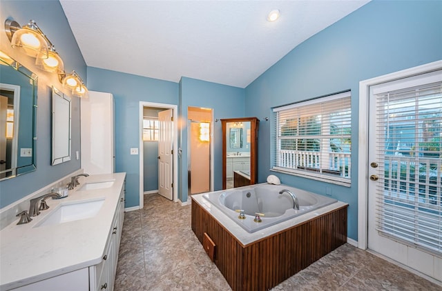 bathroom with lofted ceiling, a bath, and vanity