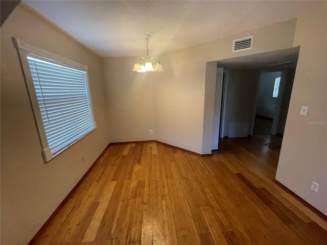 unfurnished dining area featuring hardwood / wood-style floors and a notable chandelier