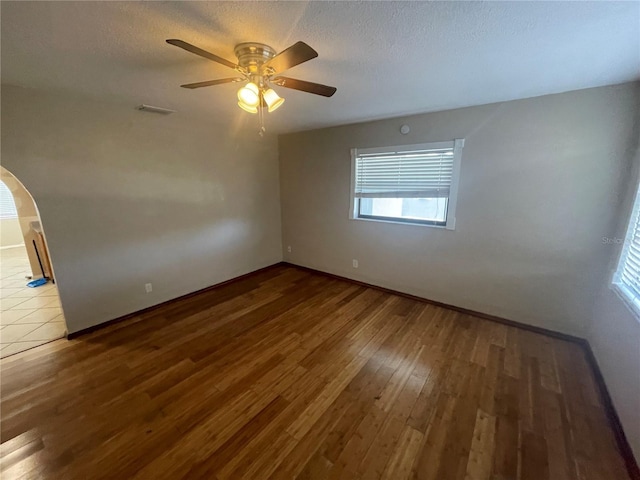 empty room featuring hardwood / wood-style flooring, ceiling fan, and a textured ceiling