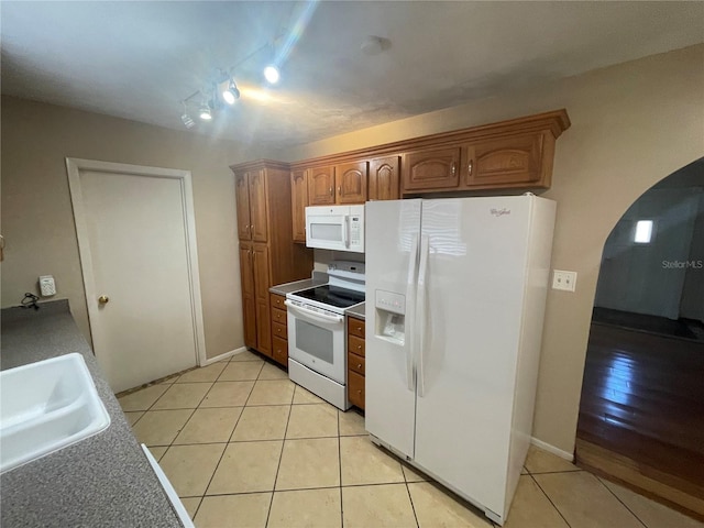 kitchen featuring white appliances, sink, and light tile patterned floors