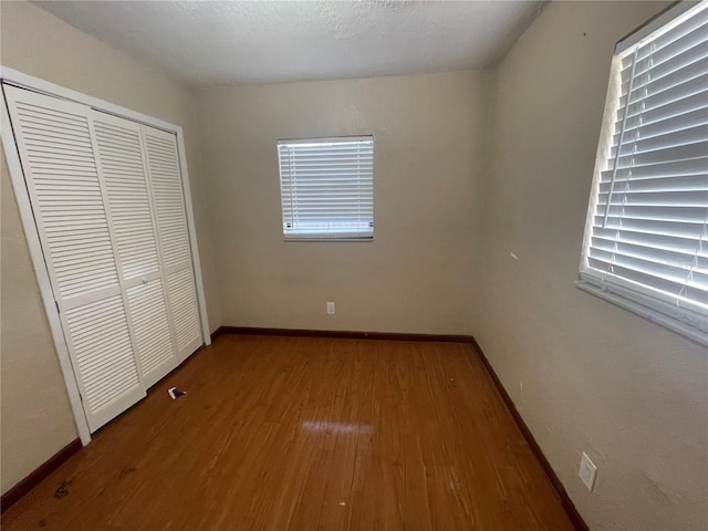 unfurnished bedroom with hardwood / wood-style flooring, a closet, and a textured ceiling