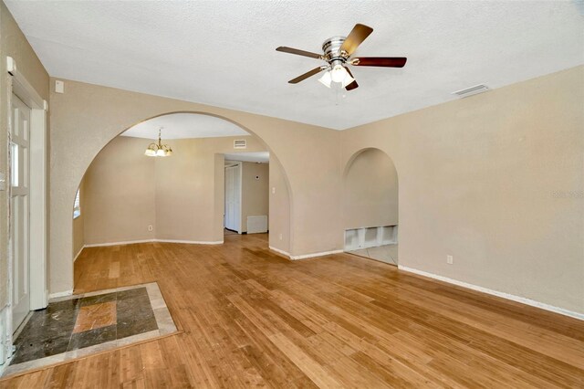 540 Florida Cir S, Apollo Beach, FL 33572 - unfurnished room featuring a textured ceiling, arched walkways, ceiling fan, visible vents, and wood finished floors