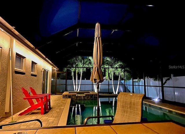 pool at night with a lanai and a patio