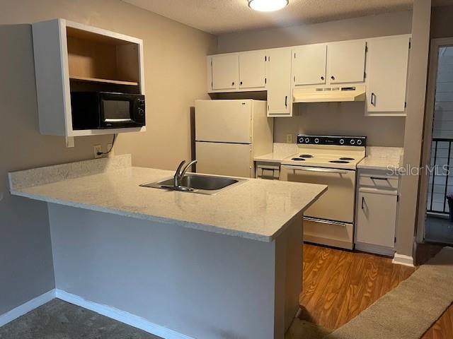 kitchen featuring sink, white cabinets, white appliances, and kitchen peninsula