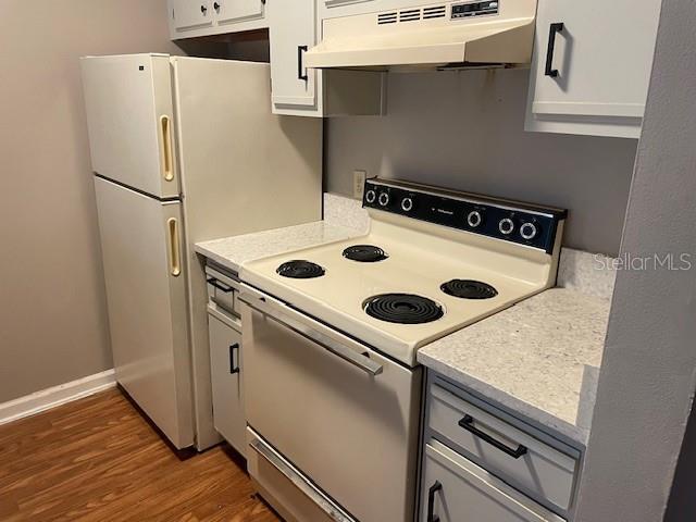 kitchen with white electric range, dark hardwood / wood-style floors, and white cabinets