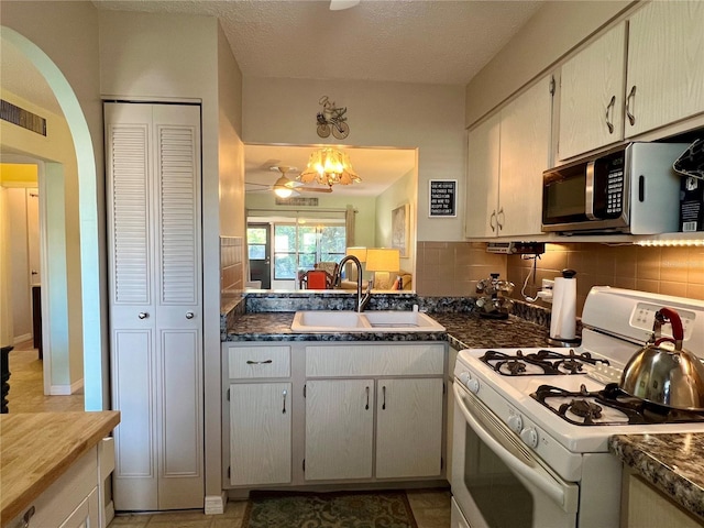 kitchen with sink, white gas stove, backsplash, and a textured ceiling