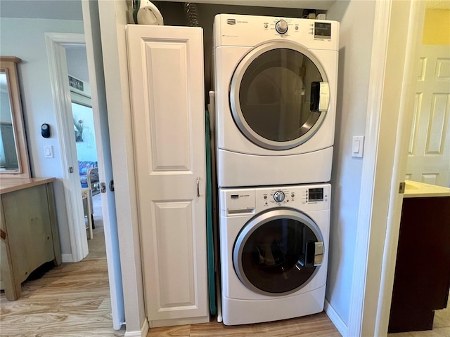 clothes washing area with cabinets, stacked washing maching and dryer, and light hardwood / wood-style floors