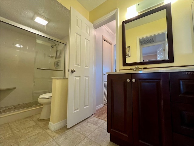 bathroom featuring vanity, a textured ceiling, a shower with door, and toilet