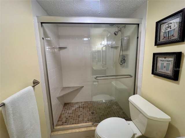 bathroom with toilet, a shower with shower door, and a textured ceiling