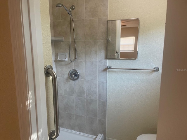 bathroom with a tile shower and toilet