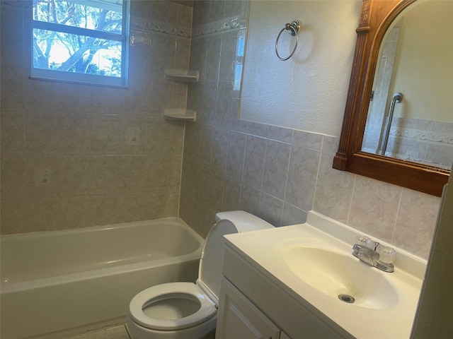 full bathroom featuring vanity, tiled shower / bath, tile walls, and toilet