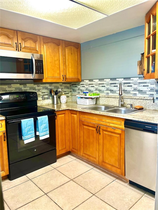 kitchen featuring sink, light tile patterned floors, appliances with stainless steel finishes, tasteful backsplash, and a textured ceiling