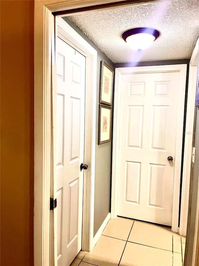 hallway featuring light tile patterned floors and a textured ceiling