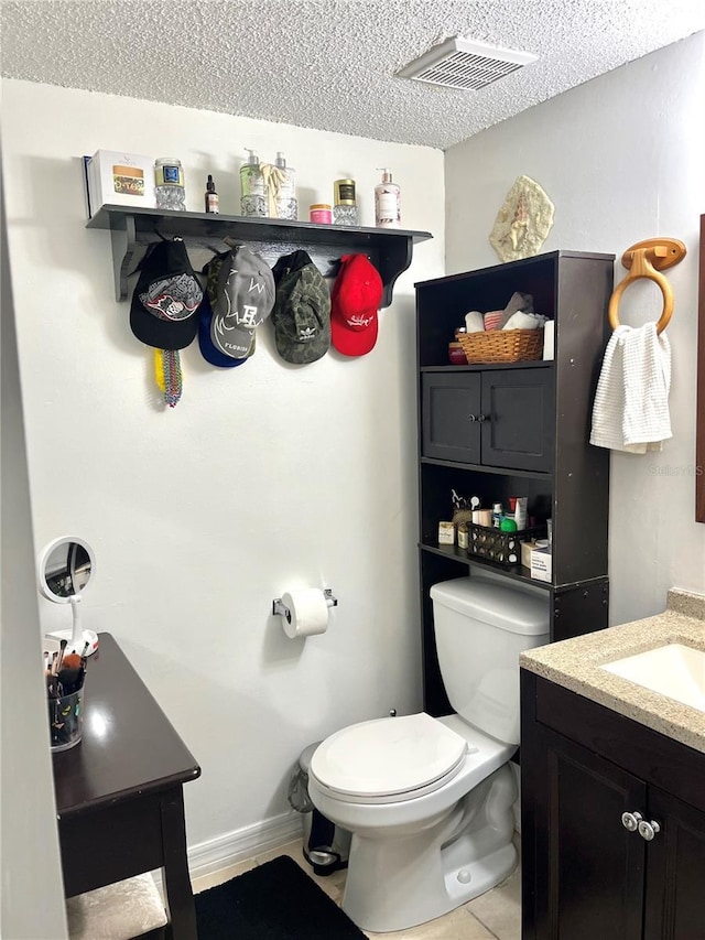 bathroom featuring vanity, a textured ceiling, tile patterned floors, and toilet