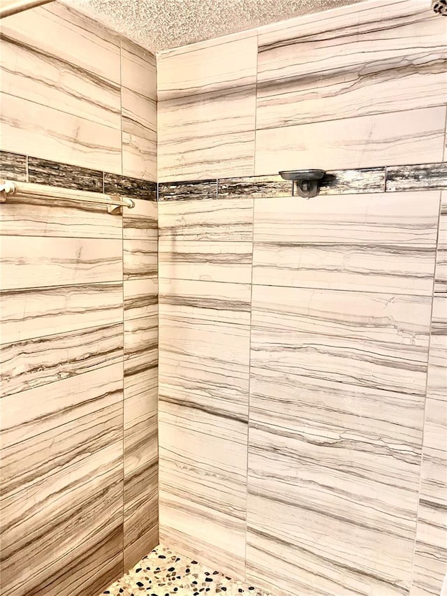 bathroom with a tile shower and a textured ceiling