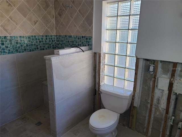 bathroom featuring toilet and tile walls