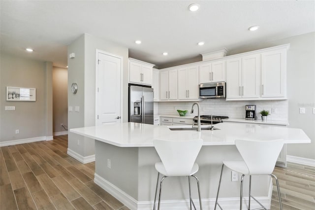 kitchen with sink, appliances with stainless steel finishes, a kitchen breakfast bar, a large island, and white cabinets