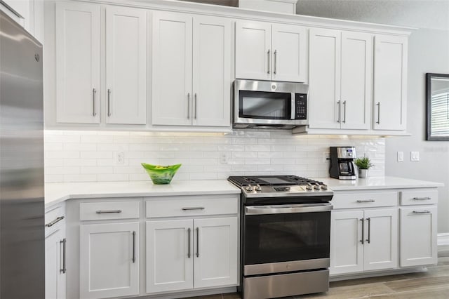 kitchen with appliances with stainless steel finishes, light hardwood / wood-style flooring, decorative backsplash, and white cabinets