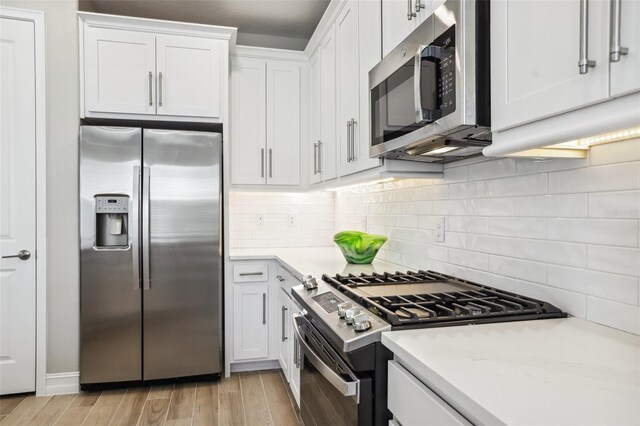 kitchen with white cabinetry, light wood-type flooring, tasteful backsplash, and appliances with stainless steel finishes