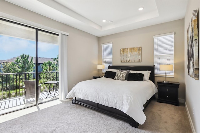 carpeted bedroom featuring a tray ceiling and access to exterior