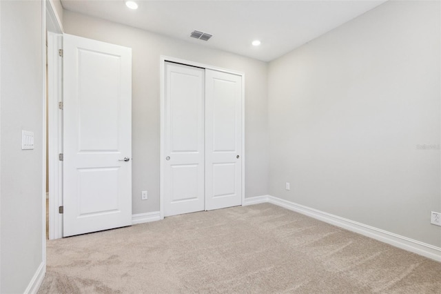 unfurnished bedroom featuring light colored carpet and a closet