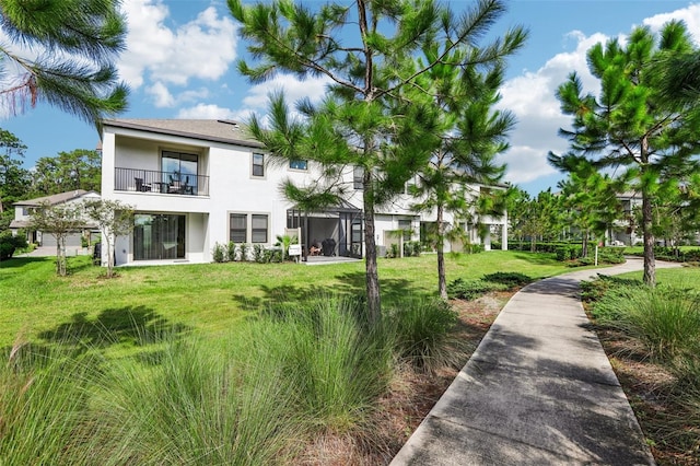 rear view of property featuring a lawn and a balcony