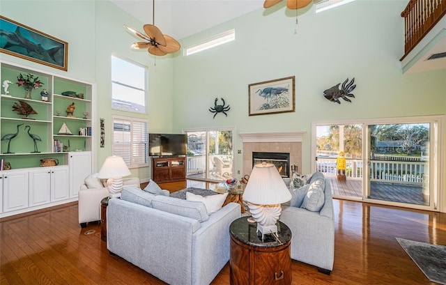 living room with a towering ceiling, a fireplace, dark hardwood / wood-style floors, and ceiling fan