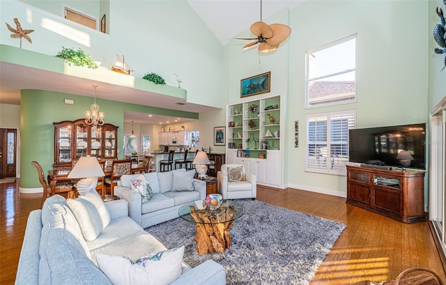 living room with hardwood / wood-style flooring, a high ceiling, and ceiling fan with notable chandelier