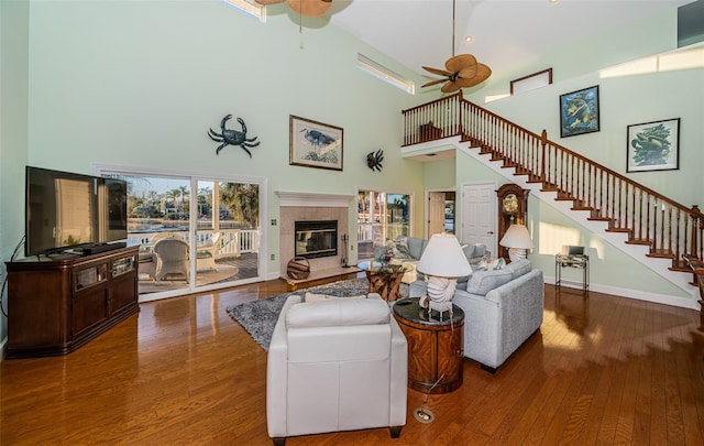 living room featuring ceiling fan, wood-type flooring, a fireplace, and a wealth of natural light