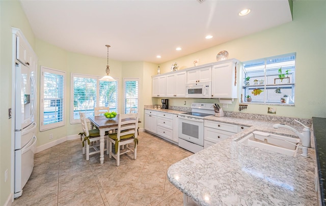 kitchen featuring sink, white cabinetry, pendant lighting, white appliances, and light stone countertops