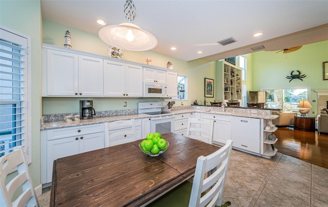 kitchen featuring a healthy amount of sunlight, hanging light fixtures, white appliances, and white cabinets