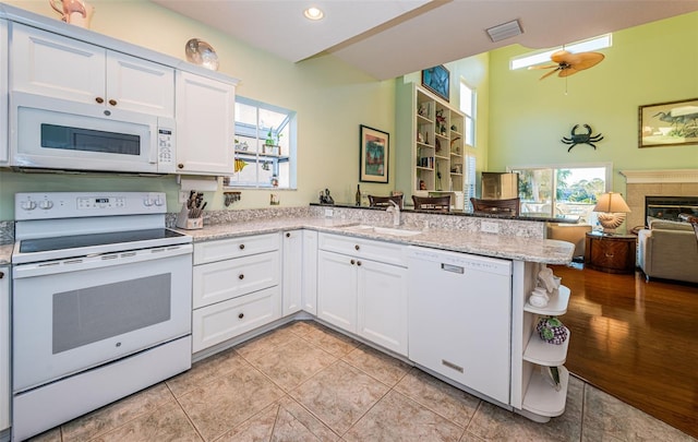 kitchen with sink, white appliances, white cabinetry, a fireplace, and kitchen peninsula