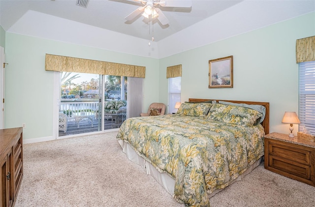 carpeted bedroom with ceiling fan, a tray ceiling, and access to outside