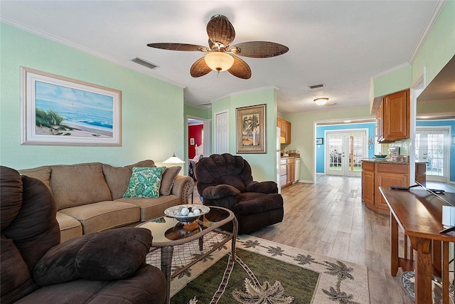 living room with ceiling fan, ornamental molding, and light wood-type flooring