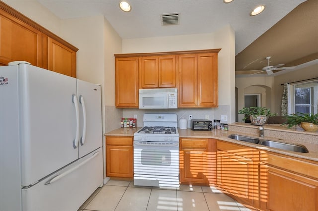 kitchen featuring sink, decorative backsplash, light tile patterned floors, ceiling fan, and white appliances