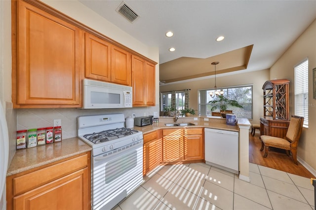 kitchen featuring sink, white appliances, an inviting chandelier, hanging light fixtures, and a tray ceiling