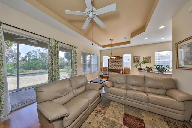 living room featuring hardwood / wood-style floors, a tray ceiling, and ceiling fan