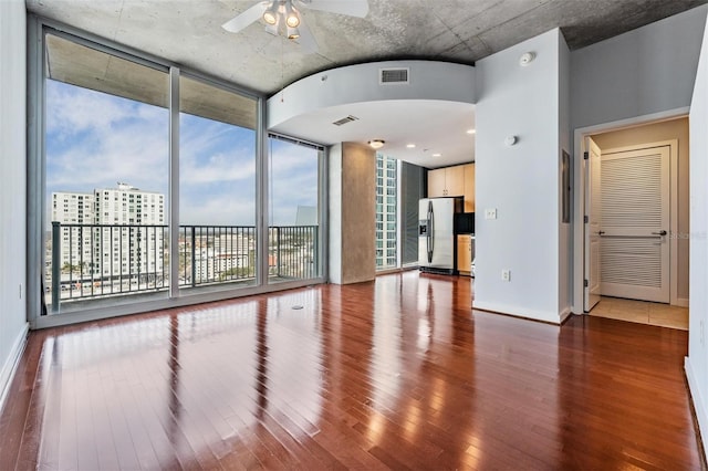 unfurnished room with hardwood / wood-style flooring, ceiling fan, and a wall of windows