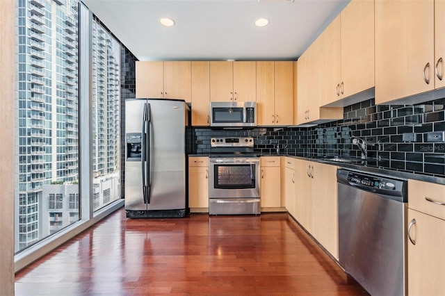 kitchen featuring appliances with stainless steel finishes, dark hardwood / wood-style floors, sink, backsplash, and light brown cabinets