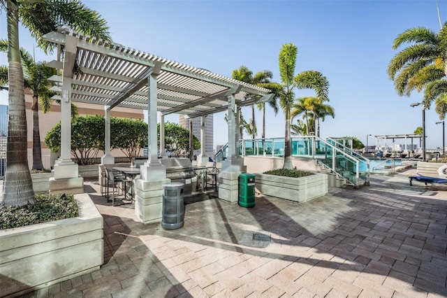 view of patio / terrace featuring a community pool, a pergola, and exterior kitchen