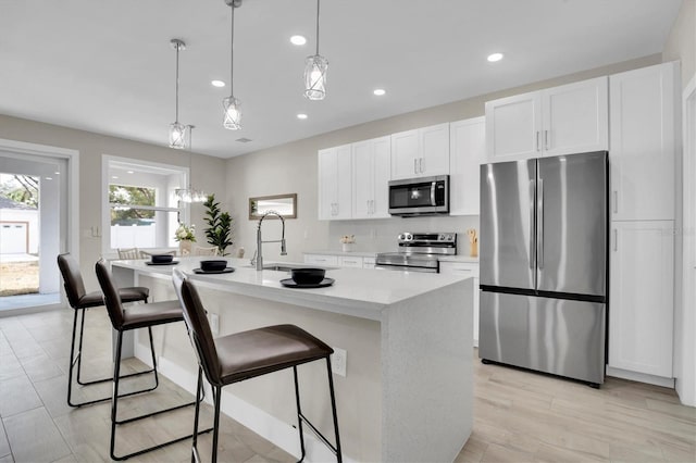 kitchen featuring white cabinetry, an island with sink, appliances with stainless steel finishes, and pendant lighting