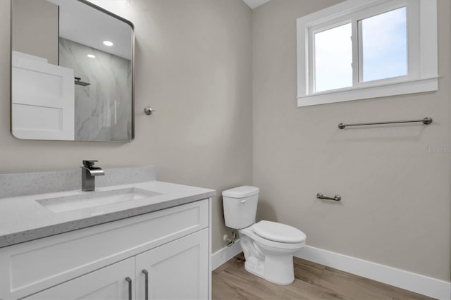 bathroom featuring vanity, a shower, hardwood / wood-style floors, and toilet