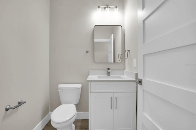 bathroom with vanity, toilet, and hardwood / wood-style floors