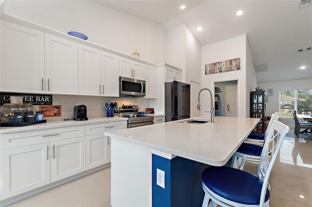 kitchen featuring white cabinetry, sink, a kitchen bar, a kitchen island with sink, and stainless steel appliances