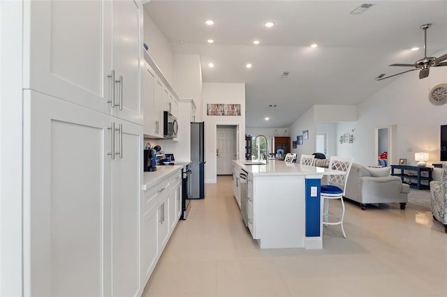 kitchen with sink, white cabinetry, stainless steel appliances, a kitchen breakfast bar, and a center island with sink