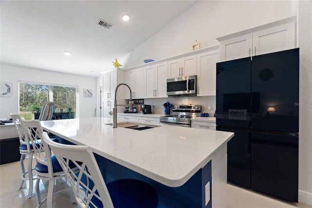 kitchen with a breakfast bar, sink, a center island with sink, stainless steel appliances, and white cabinets