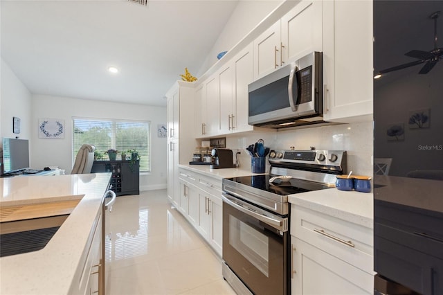 kitchen featuring white cabinetry, light stone counters, tasteful backsplash, light tile patterned floors, and appliances with stainless steel finishes