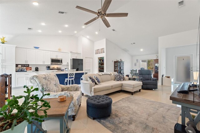 tiled living room with ceiling fan and high vaulted ceiling